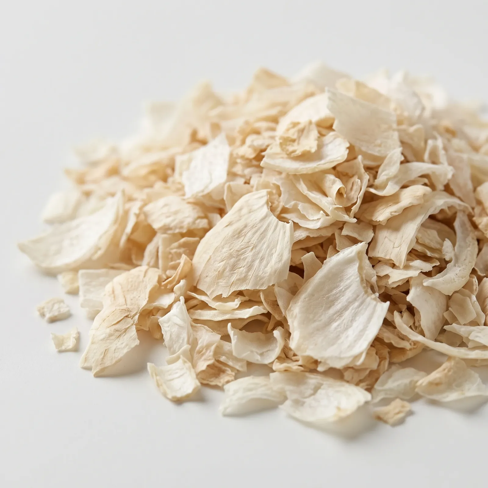 A heap of dried white onion flakes on a white surface