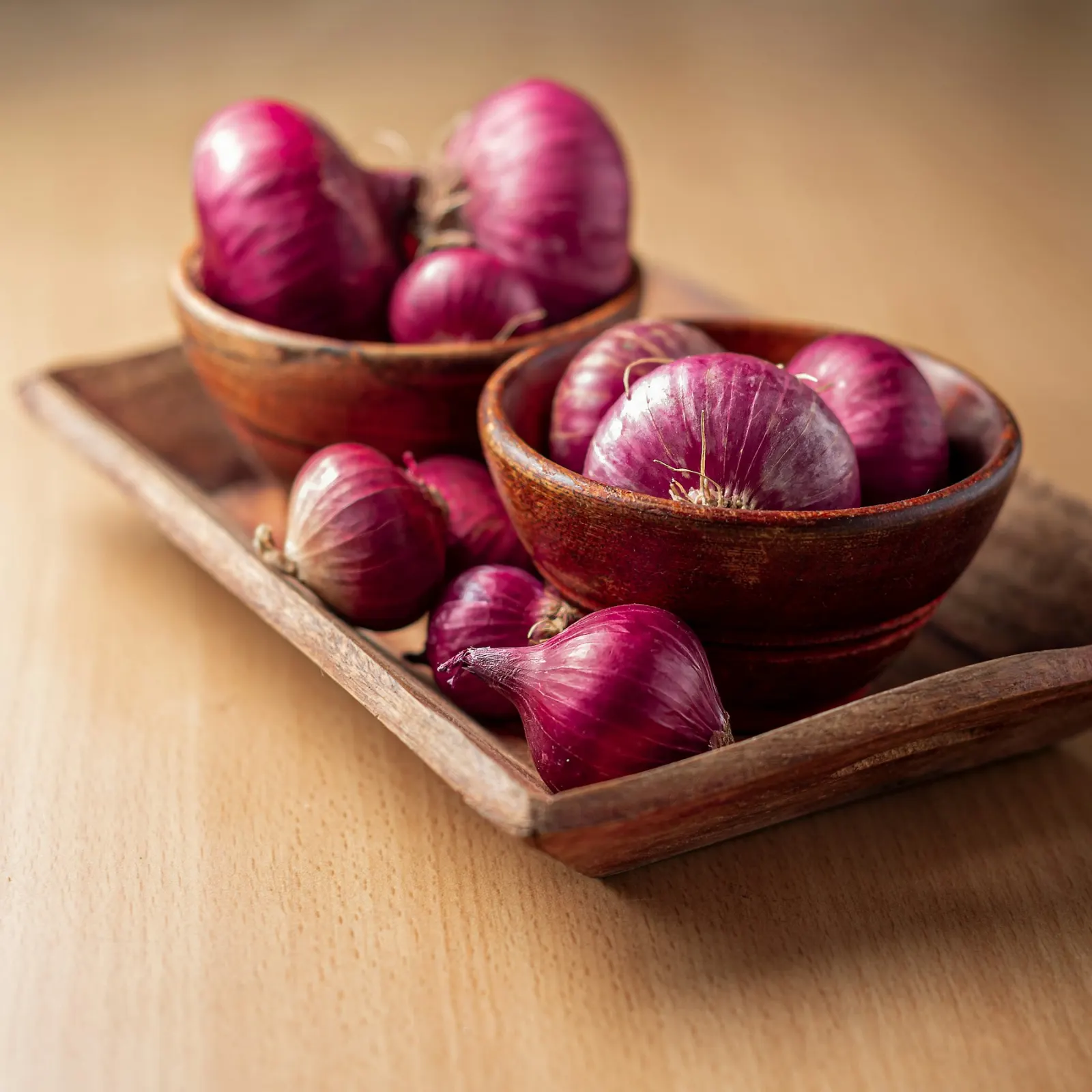 Fresh red onions in wooden bowls on a wooden tray